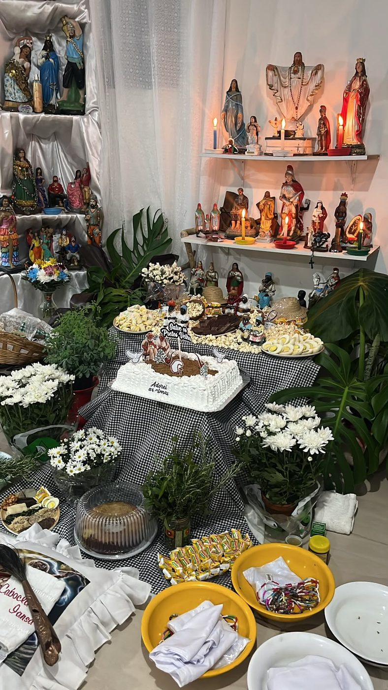 Congá da casa com imagens dos santos, comidas e flores